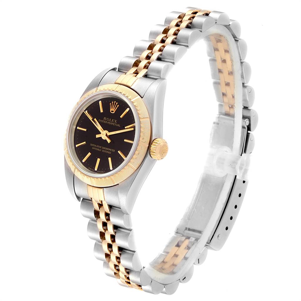 This Rolex Oyster Perpetual 76243 Women
s Steel and Gold (two tone) Black Dial 76243 Women
s Steel and Gold (two tone) Black Dial watch is shown at an oblique angle, highlighting the gold bezel, black dial, and two-tone bracelet.