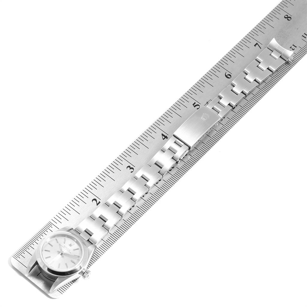 The image shows a Rolex Oyster Perpetual 76080 Women's Stainless Steel Silver Dial 76080 Women's Stainless Steel Silver Dial watch, laying flat on a ruler, displaying the watch face and bracelet.