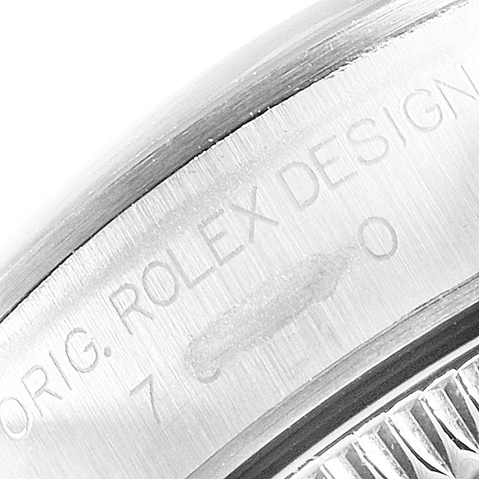 This image shows a macro shot of the casing edge of a Rolex Oyster Perpetual 76080 Women's Stainless Steel Silver Dial 76080 Women's Stainless Steel Silver Dial watch, highlighting the engraved text.