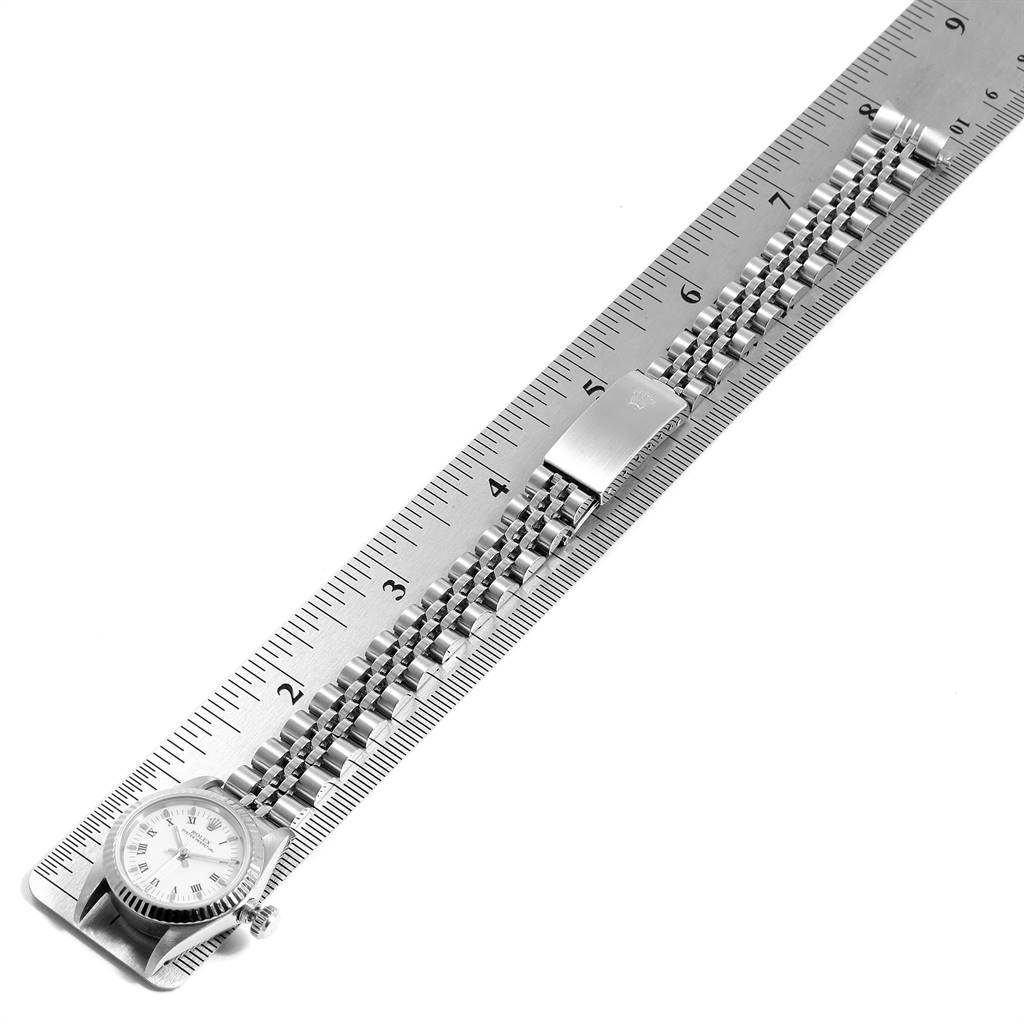 This image shows a Rolex Oyster Perpetual 67194 Women
s Stainless Steel White Dial 67194 Women
s Stainless Steel White Dial watch with its bracelet placed next to a ruler for measurement.