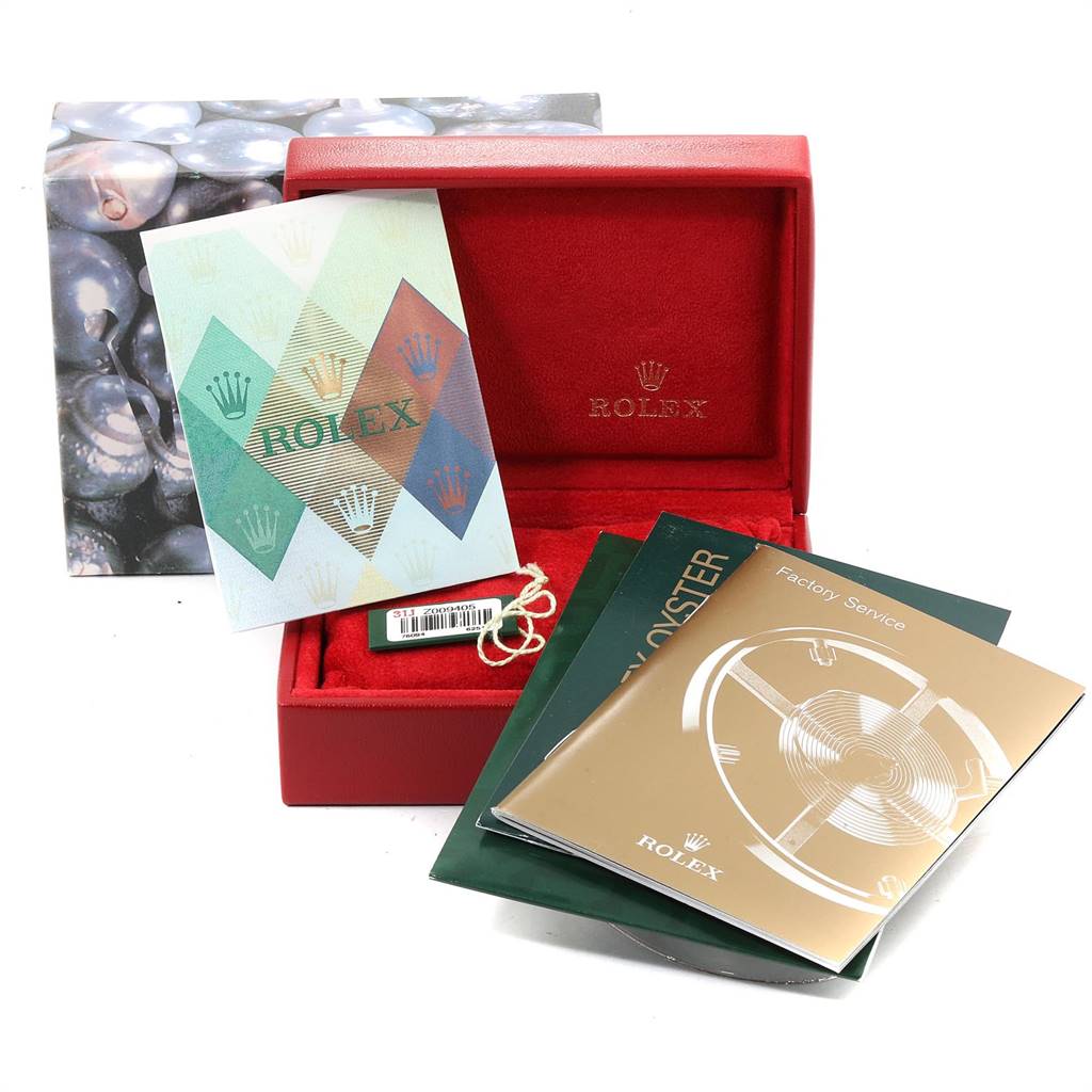 The image shows a Rolex Oyster Perpetual 76094 Women's Stainless Steel Silver Dial 76094 Women's Stainless Steel Silver Dial watch box with various booklets and a tag placed inside and around the box.