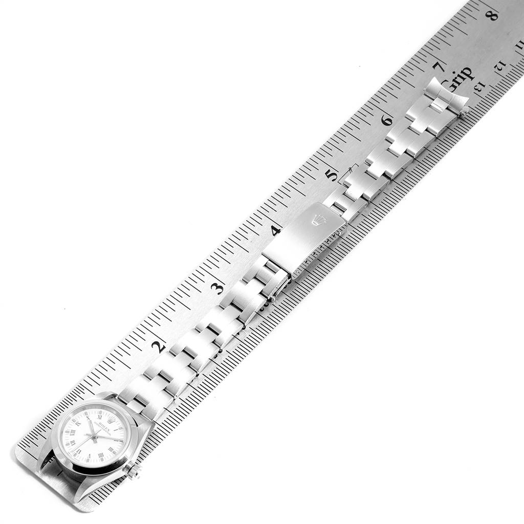 The image shows a Rolex Oyster Perpetual 76080 Women
s Stainless Steel White Dial 76080 Women
s Stainless Steel White Dial watch and bracelet laid against a ruler, with the watch face partially visible.