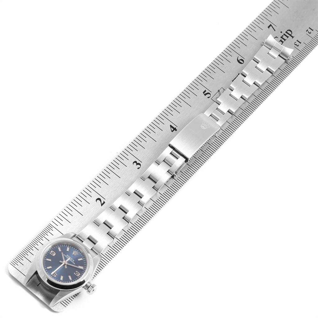 The image shows a Rolex Oyster Perpetual 76080 Women's Stainless Steel Blue Dial 76080 Women's Stainless Steel Blue Dial watch laid flat alongside a ruler, focusing on the watch band and clasp.