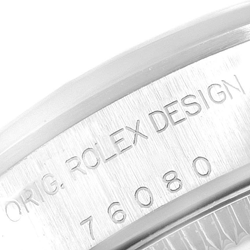 This image shows an engraved section of the Rolex Oyster Perpetual 76080 Women's Stainless Steel Blue Dial 76080 Women's Stainless Steel Blue Dial watch case, including the words "ORIG ROLEX DESIGN" and the model number.