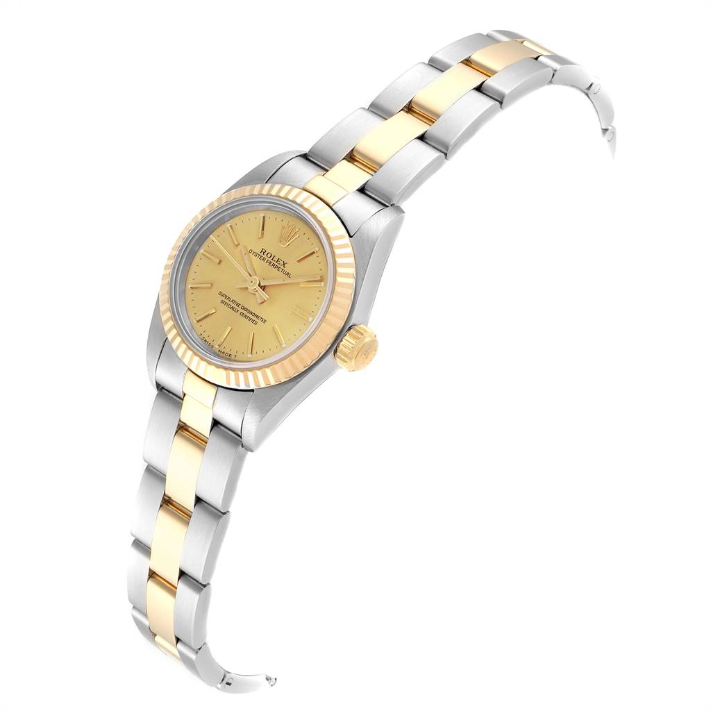 The Rolex Oyster Perpetual 67193 Women's Stainless Steel Champagne Dial 67193 Women's Stainless Steel Champagne Dial watch is shown from an angled top-down view, displaying its gold dial, fluted bezel, and two-tone bracelet.