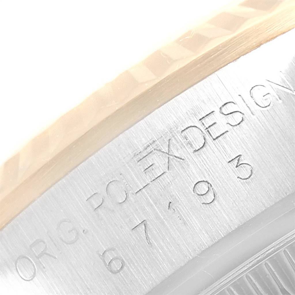 The image shows a close-up of the side of a Rolex Oyster Perpetual 67193 Women
s Steel and Gold (two tone) Champagne Dial 67193 Women
s Steel and Gold (two tone) Champagne Dial watch, featuring the engraved "Rolex Design" text and serial number.