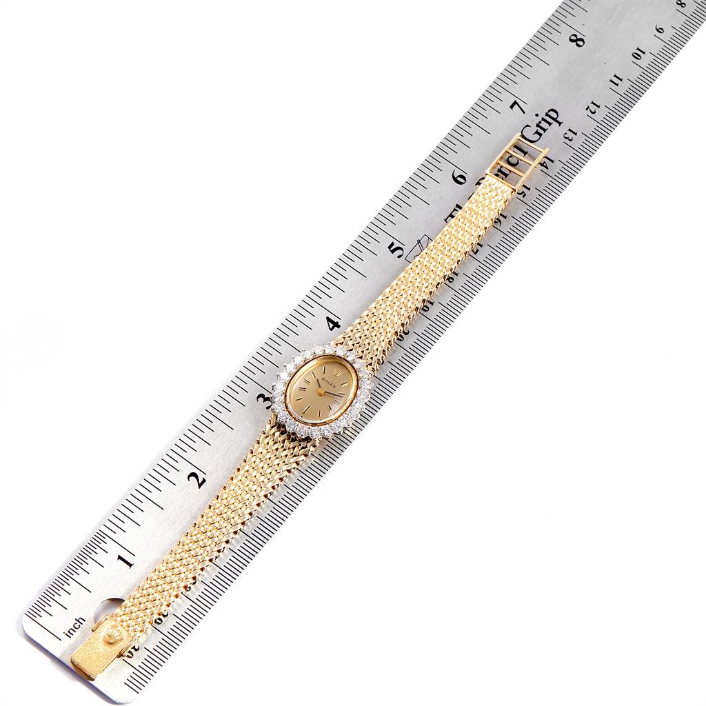 The image shows a Rolex Oyster Perpetual Women
s Yellow Gold Champagne Dial Women
s Yellow Gold Champagne Dial watch placed next to a ruler, displaying its gold bracelet and watch face.