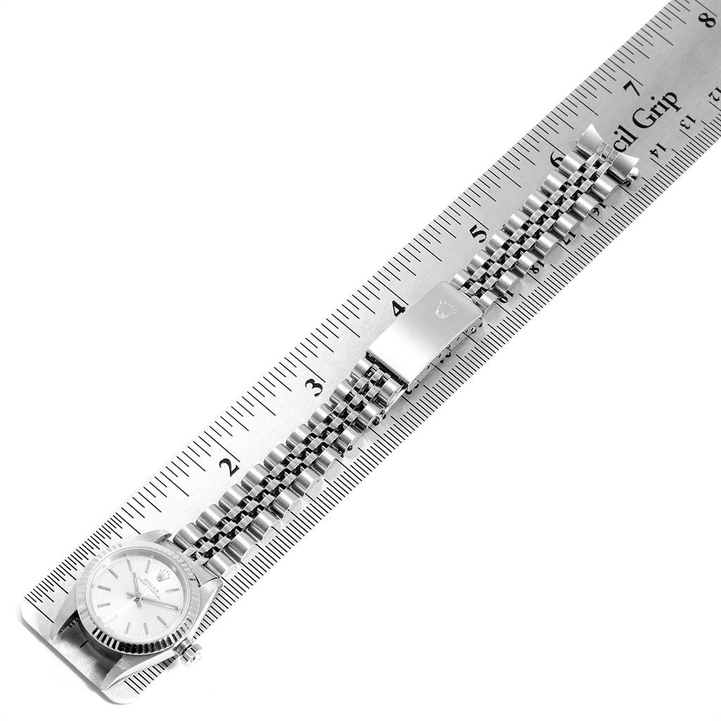This image shows the Rolex Oyster Perpetual 76094 Women's Stainless Steel Silver Dial 76094 Women's Stainless Steel Silver Dial watch laid flat on a ruler, displaying its face and bracelet.