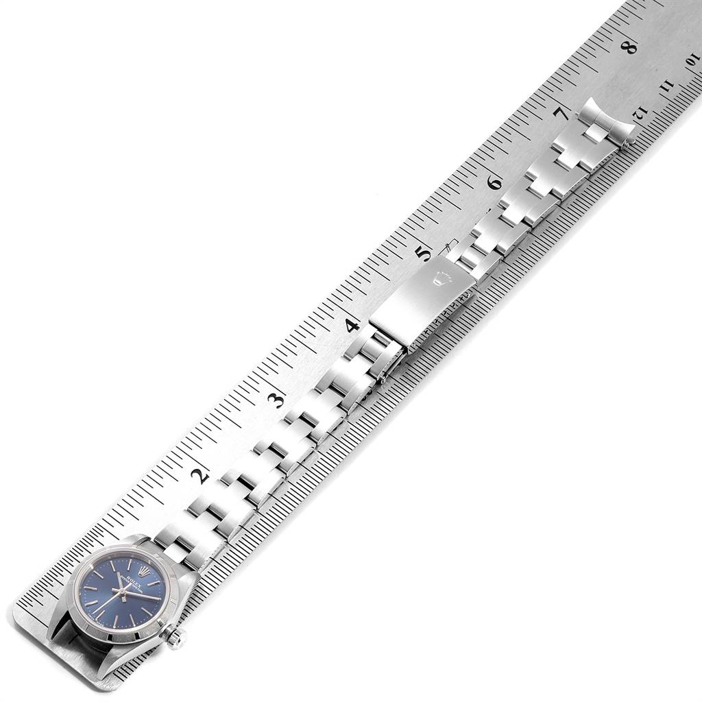The image shows a Rolex Oyster Perpetual 76030 Women
s Stainless Steel Blue Dial 76030 Women
s Stainless Steel Blue Dial watch placed alongside a ruler, highlighting its bracelet and clasp.