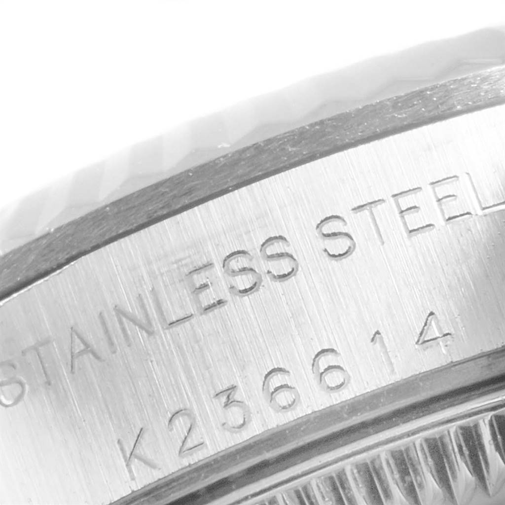 The image shows a close-up of the side of a Rolex Oyster Perpetual 76094 Women's Stainless Steel Silver Dial 76094 Women's Stainless Steel Silver Dial watch, focusing on the engraved serial numbers and "STAINLESS STEEL."