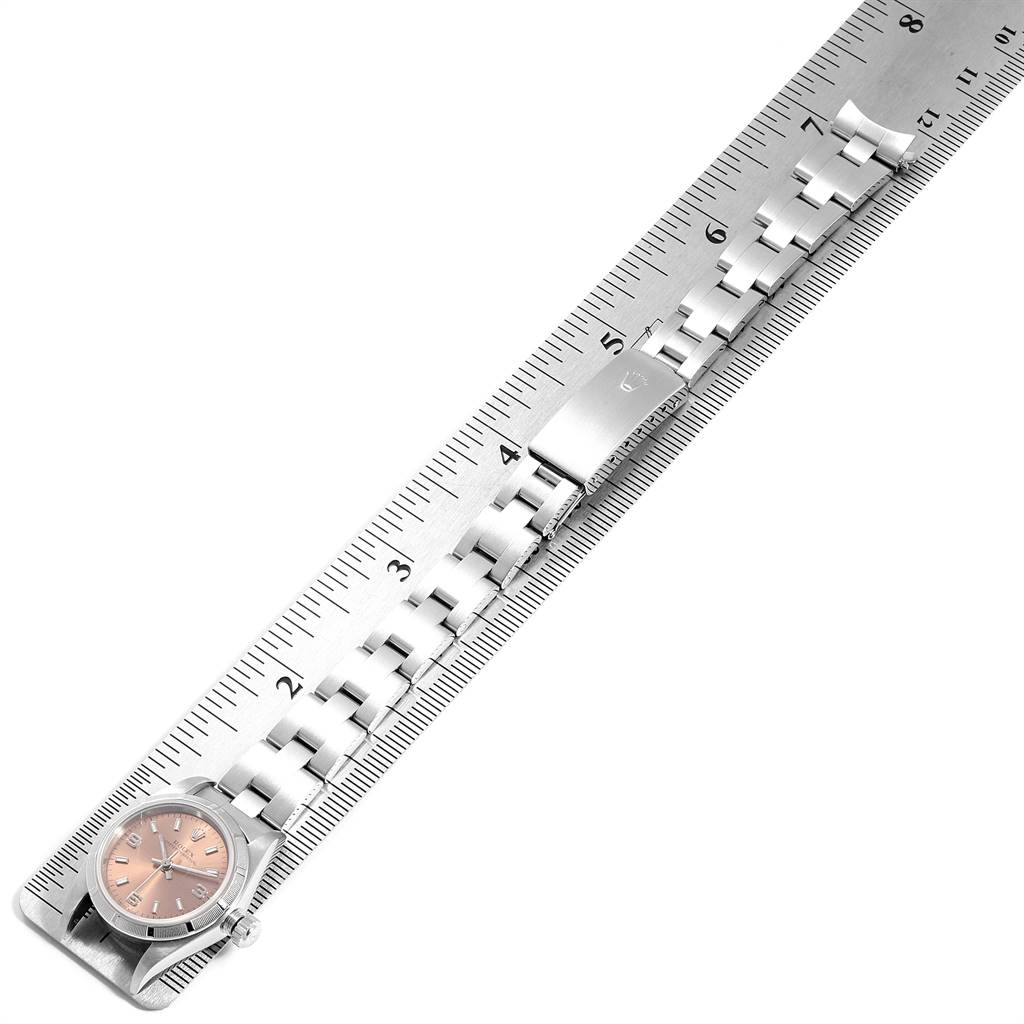 The image shows a Rolex Oyster Perpetual 76030 Women's Stainless Steel Pink Dial 76030 Women's Stainless Steel Pink Dial watch laid flat on a ruler, displaying the watch's face and bracelet.