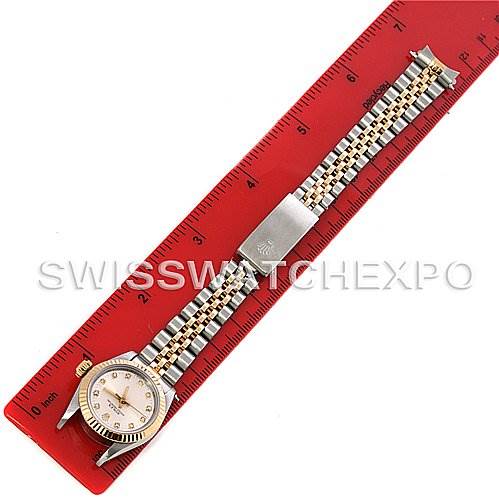 The Rolex Oyster Perpetual 67193 Women's Steel and Gold (two tone) Silver Dial 67193 Women's Steel and Gold (two tone) Silver Dial watch is shown from a top-down angle, displaying the face, bracelet, and clasp against a red ruler.