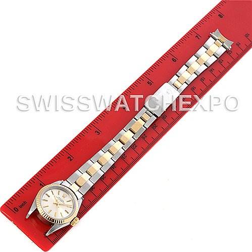 The image shows a Rolex Oyster Perpetual 67193 Women's Steel and Gold (two tone) Silver Dial 67193 Women's Steel and Gold (two tone) Silver Dial watch laid flat alongside a red ruler, showcasing its entire band and face.