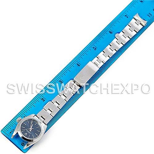 The image shows a Rolex Oyster Perpetual 67180 Women's Stainless Steel Blue Dial 67180 Women's Stainless Steel Blue Dial watch placed alongside a blue ruler, displaying the watch's full length and metal bracelet.