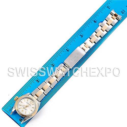 The image shows a Rolex Oyster Perpetual 67193 Women
s Steel and Gold (two tone) Silver Dial 67193 Women
s Steel and Gold (two tone) Silver Dial watch laid flat with its entire bracelet alongside a blue ruler for measurement.
