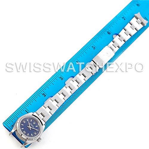 This image shows a Rolex Oyster Perpetual 76030 Women's Stainless Steel Blue Dial 76030 Women's Stainless Steel Blue Dial watch with a blue dial, silver bracelet, and clasp next to a ruler, viewed from the top.