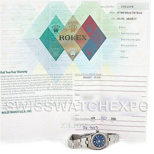 The image shows a Rolex Oyster Perpetual 76030 Women's Stainless Steel Blue Dial 76030 Women's Stainless Steel Blue Dial watch with a blue dial placed in front of its warranty and documentation papers.