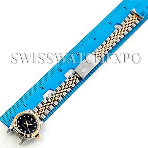 The image shows a Rolex Oyster Perpetual 76193 Women's Steel and Gold (two tone) Black Dial 76193 Women's Steel and Gold (two tone) Black Dial watch from a top-down angle, featuring the watch face, bezel, and bracelet against a ruler.