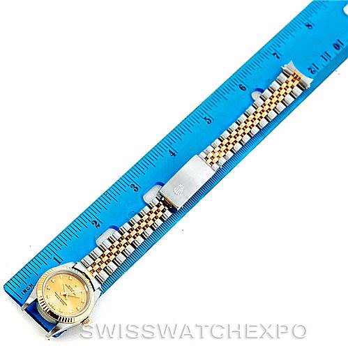The image shows a Rolex Oyster Perpetual 76193 Women's Steel and Gold (two tone) Champagne Dial 76193 Women's Steel and Gold (two tone) Champagne Dial watch from a top-down angle, measured against a blue ruler, displaying the full bracelet and clasp.