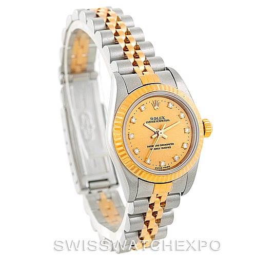 The image shows a Rolex Oyster Perpetual 76193 Women's Steel and Gold (two tone) Champagne Dial 76193 Women's Steel and Gold (two tone) Champagne Dial watch at an angle displaying its face, bezel, and two-tone bracelet.
