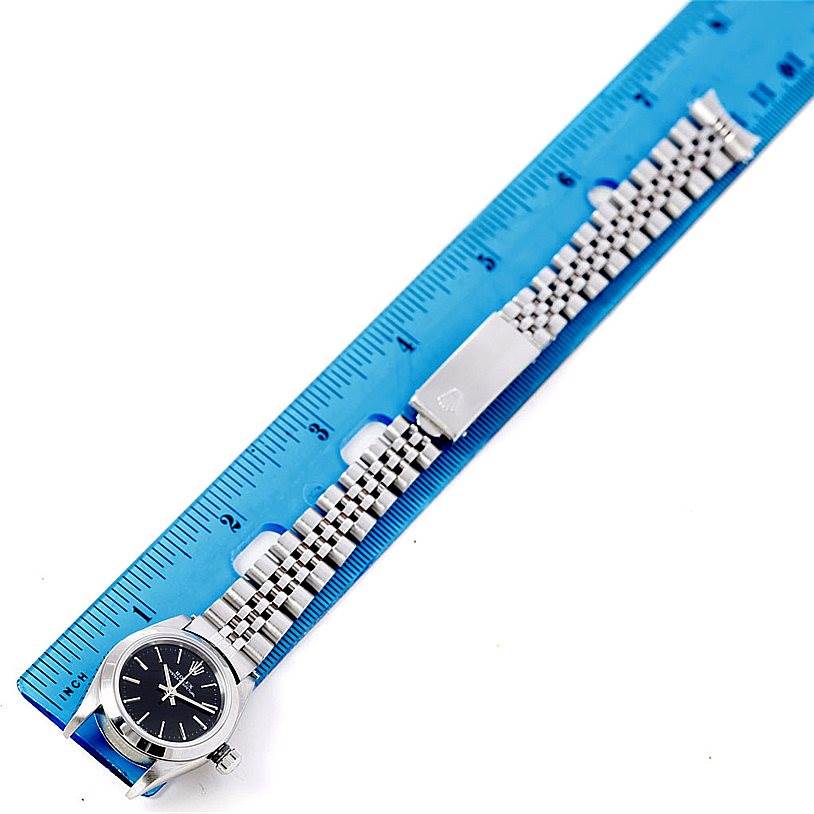 The image shows a Rolex Oyster Perpetual 76080 Women's Stainless Steel Black Dial 76080 Women's Stainless Steel Black Dial watch laid flat next to a blue ruler, displaying the watch face and full bracelet.