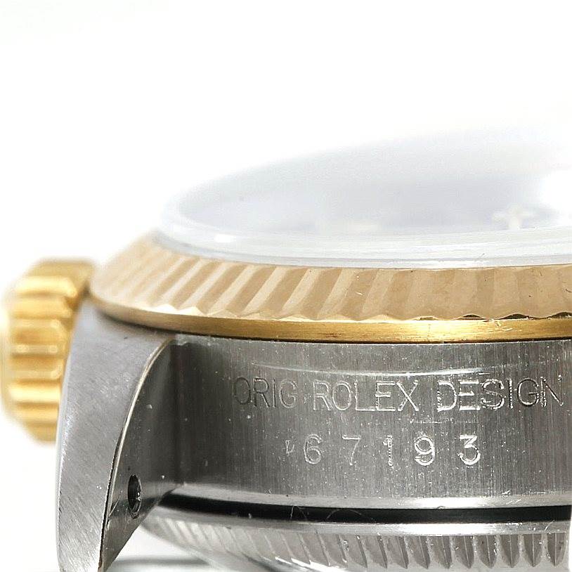 The image shows a close-up of the side of a Rolex Oyster Perpetual 67193 Women's Steel and Gold (two tone) Black Dial 67193 Women's Steel and Gold (two tone) Black Dial watch, highlighting the crown, bezel, and case with engraving.