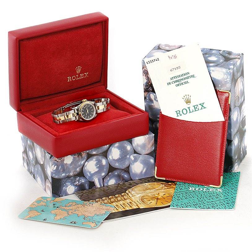 The image shows a Rolex Oyster Perpetual 67193 Women's Steel and Gold (two tone) Black Dial 67193 Women's Steel and Gold (two tone) Black Dial watch in its box, accompanied by a certification booklet and additional cards.