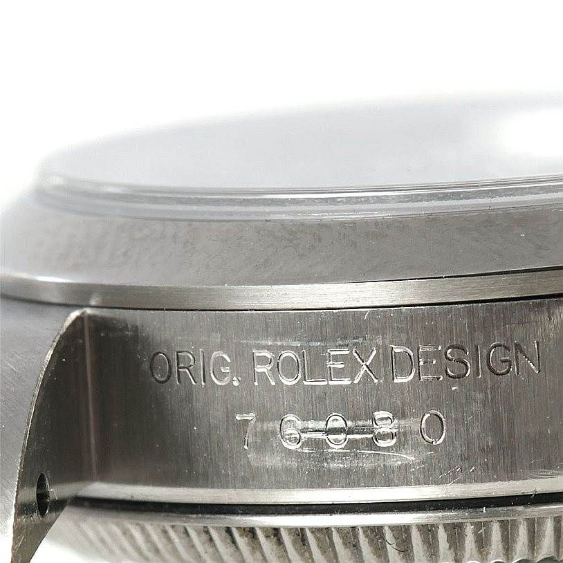 The image shows a close-up of the case of the Rolex Oyster Perpetual 76080 Women's Stainless Steel Blue Dial 76080 Women's Stainless Steel Blue Dial watch, displaying the model number and “Orig. Rolex Design."