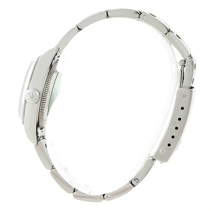 This side view of the Rolex Oyster Perpetual 76080 Women's Stainless Steel Blue Dial 76080 Women's Stainless Steel Blue Dial watch shows the crown, case, bracelet, and clasp.