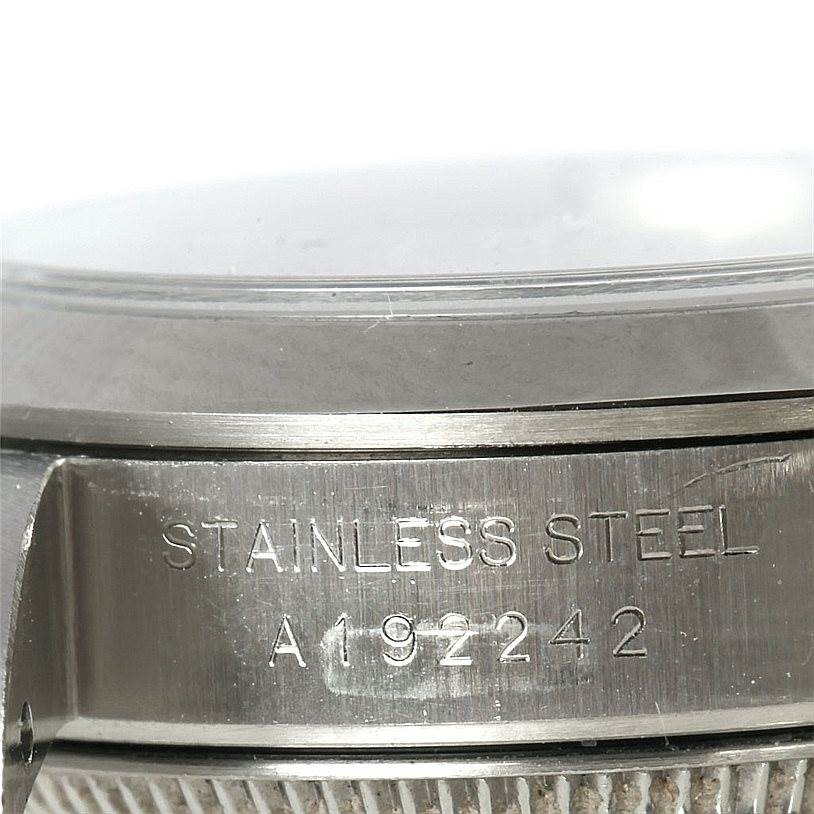 The image shows a close-up of the side of a Rolex Oyster Perpetual 76080 Women's Stainless Steel Blue Dial 76080 Women's Stainless Steel Blue Dial watch case, focusing on the engraved serial number and "Stainless Steel" marking.