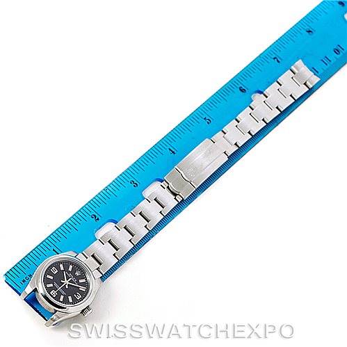 The image shows a top-down view of a Rolex Oyster Perpetual 176200 Women's Stainless Steel Black Dial 176200 Women's Stainless Steel Black Dial watch laid next to a blue ruler, highlighting the watch dial and bracelet.