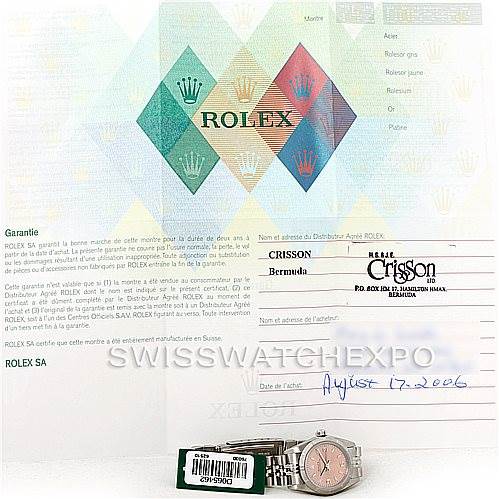 The image shows warranty documents and a Rolex Oyster Perpetual 76030 Women's Stainless Steel Pink Dial 76030 Women's Stainless Steel Pink Dial watch with a partial view of the dial and bracelet.