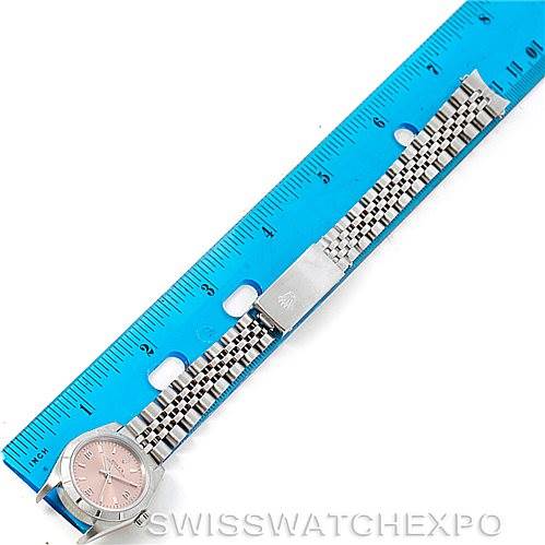 The Rolex Oyster Perpetual 76030 Women's Stainless Steel Pink Dial 76030 Women's Stainless Steel Pink Dial watch is shown laid flat with its band extended next to a ruler for size reference.