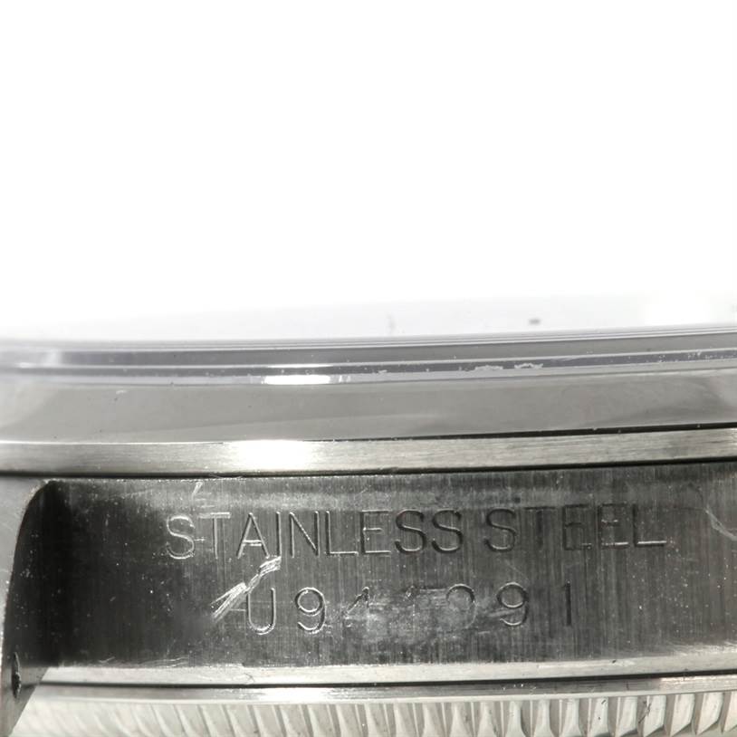 This image shows a side view of the case and bezel of the Rolex Oyster Perpetual 67180 Women's Stainless Steel Black Dial 67180 Women's Stainless Steel Black Dial watch, focusing on the "STAINLESS STEEL" engraving.