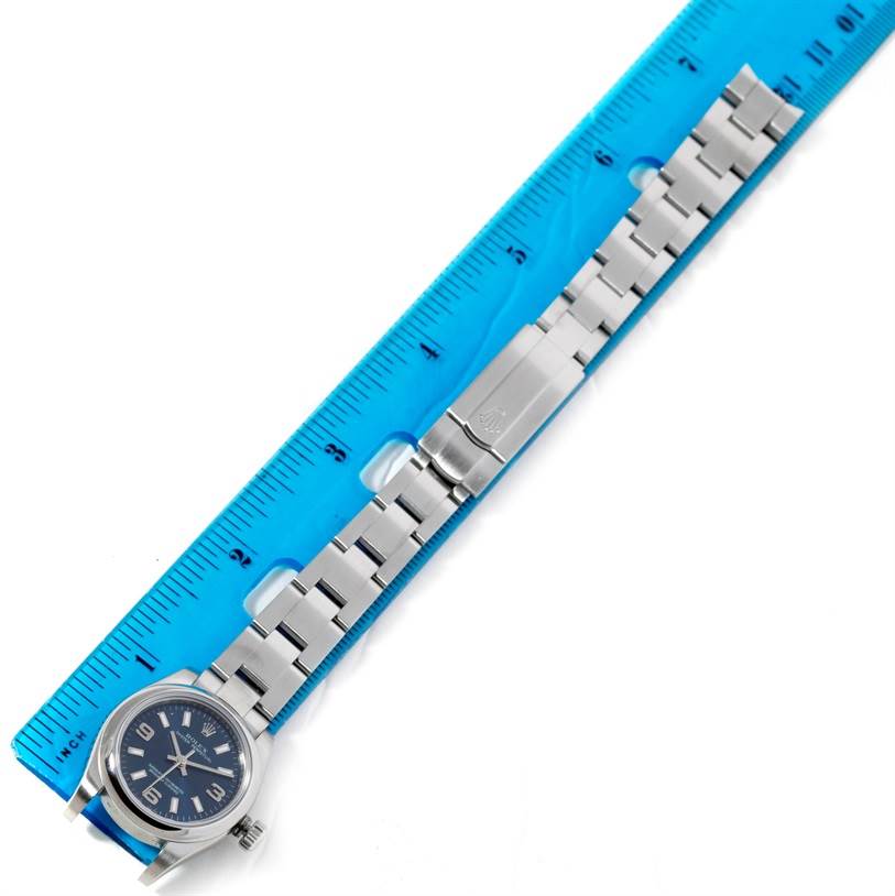 This image shows the Rolex Oyster Perpetual 176200 Women's Stainless Steel Blue Dial 176200 Women's Stainless Steel Blue Dial watch laid flat with a blue ruler measuring its bracelet length.