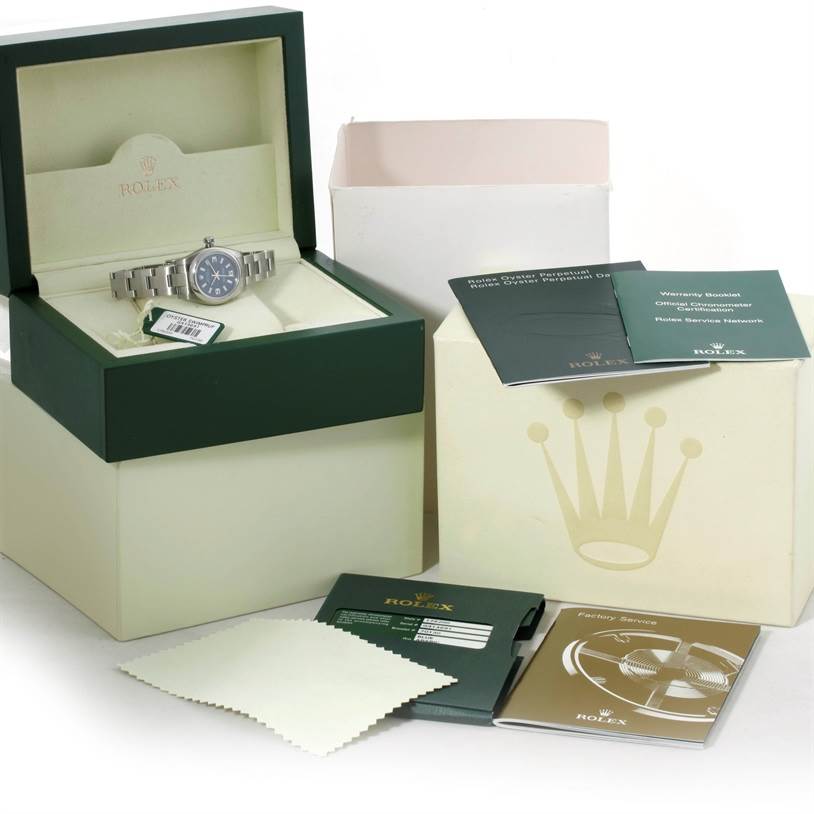 The Rolex Oyster Perpetual 176200 Women's Stainless Steel Blue Dial 176200 Women's Stainless Steel Blue Dial watch is shown from the front in its box, along with brochures, a cleaning cloth, and packaging.