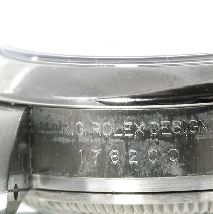 The image shows a close-up angle of the side of the case of a Rolex Oyster Perpetual 176200 Women's Stainless Steel Blue Dial 176200 Women's Stainless Steel Blue Dial watch, displaying the "ORIG. ROLEX DESIGN" engraving and model number 176200.