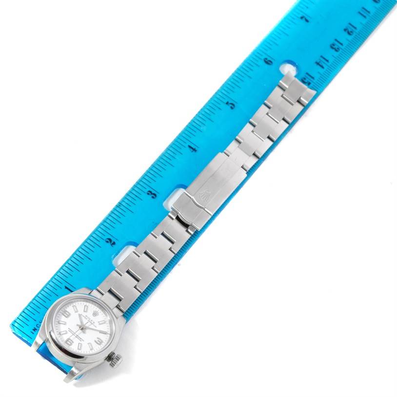 This image shows a Rolex Oyster Perpetual 176200 Women's Stainless Steel White Dial 176200 Women's Stainless Steel White Dial watch and bracelet laying flat next to a blue ruler.