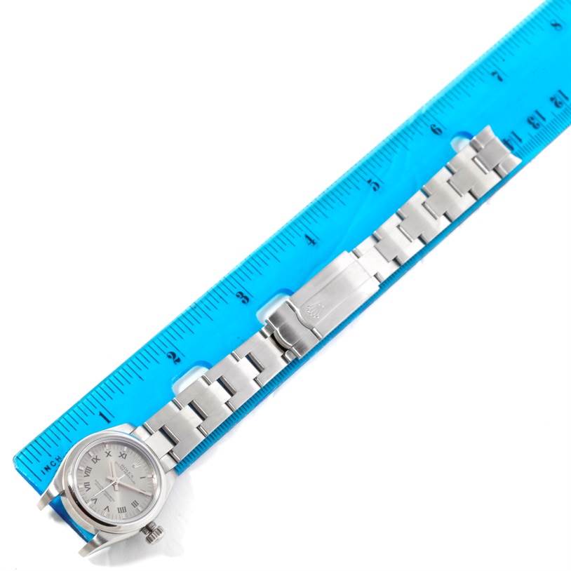 The Rolex Oyster Perpetual 176200 Women's Stainless Steel Silver Dial 176200 Women's Stainless Steel Silver Dial watch is shown from a top-down angle, displaying the face, bracelet, and clasp next to a ruler.