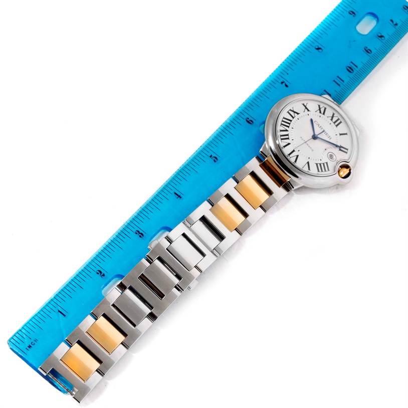The image shows a Ballon Bleu watch by Cartier with a ruler indicating the length of its two-tone bracelet, viewed from above.