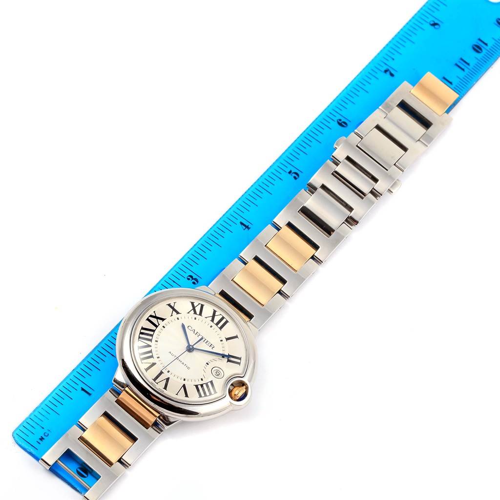 The image shows a Ballon Bleu de Cartier watch placed flat next to a ruler, highlighting the face and bracelet of the watch.