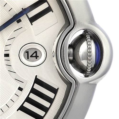 The image shows a close-up of Cartier's Ballon Bleu watch, highlighting the date window, part of the face, and the crown.