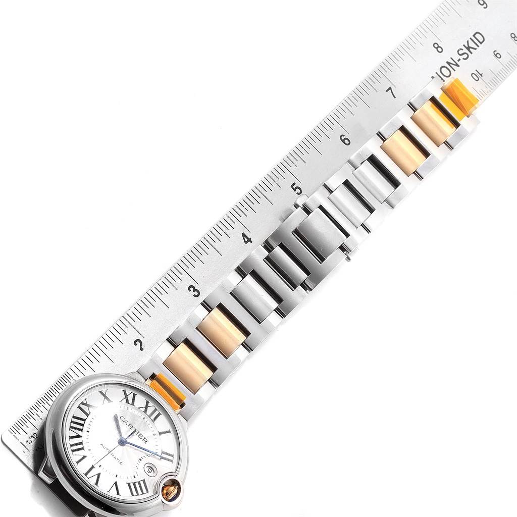 The image shows a Ballon Bleu by Cartier watch laid flat next to a ruler, highlighting its metal and gold link bracelet.