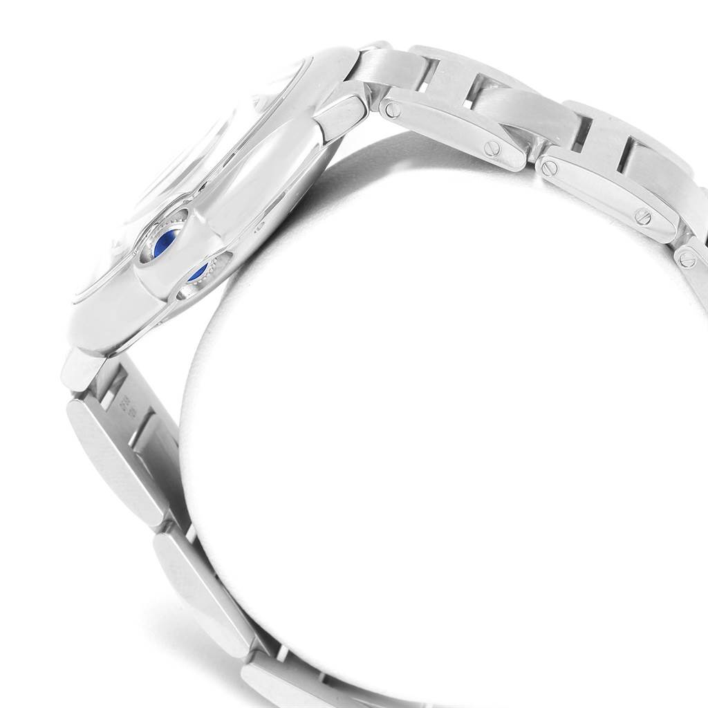 The image shows a side view of the Ballon Bleu model by Cartier, highlighting its silver bracelet and blue crown.