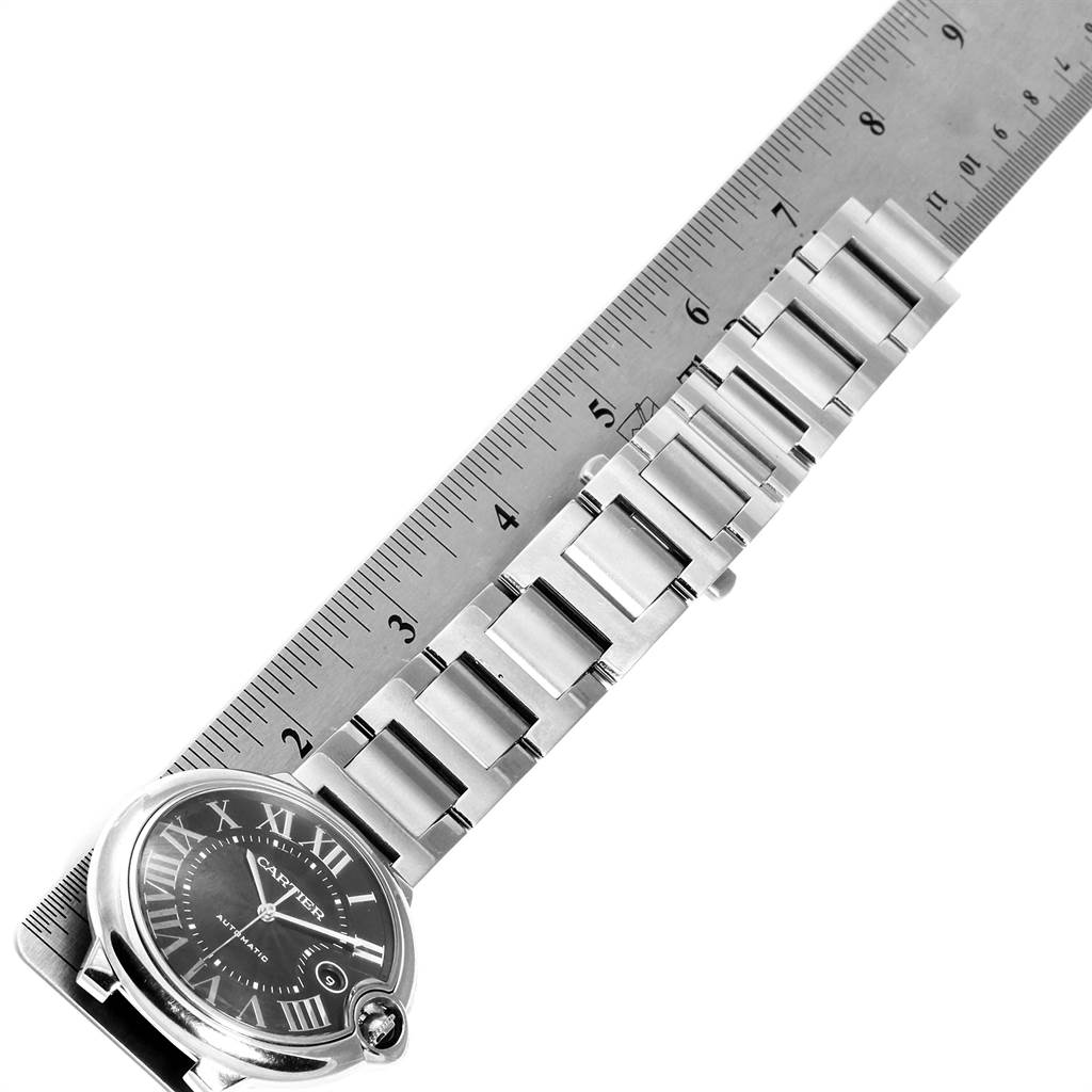 The image shows a partial top view of a Cartier Ballon Bleu W6920042 Men's Stainless Steel Black Dial W6920042 Men's Stainless Steel Black Dial watch next to a ruler, highlighting its bracelet and case.