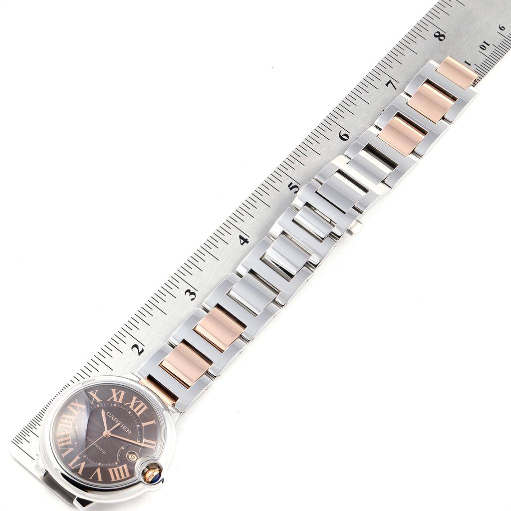 The image shows a Cartier Ballon Bleu W6920032 Men's Steel and Gold (two tone) Brown Dial W6920032 Men's Steel and Gold (two tone) Brown Dial watch with its band next to a ruler for measurement.