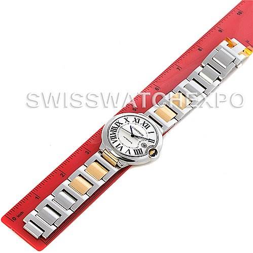 This image shows a top-down view of the Cartier Ballon Bleu W69009Z3 Men
s Stainless Steel Silver Dial W69009Z3 Men
s Stainless Steel Silver Dial watch, highlighting its face, numerals, and metallic band placed on a red ruler.