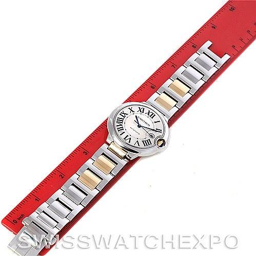This image shows an overhead view of a Cartier Ballon Bleu W69009Z3 Men
s Stainless Steel Silver Dial W69009Z3 Men
s Stainless Steel Silver Dial watch with a metal bracelet on a red measuring tape.