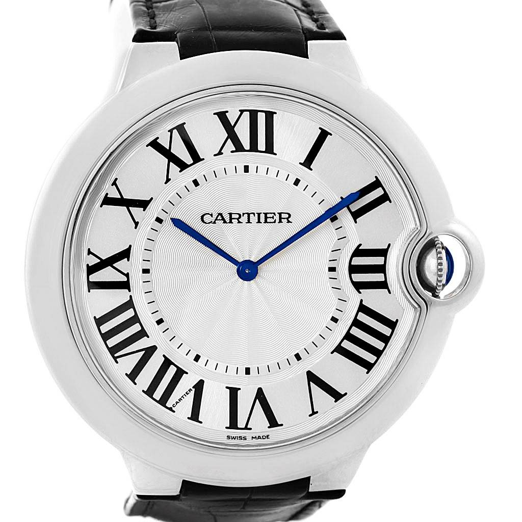 The image shows a front view of the Cartier Ballon Bleu W6920055 Men's White Gold Silver Dial W6920055 Men's White Gold Silver Dial watch, highlighting its Roman numerals, blue hands, and unique crown.