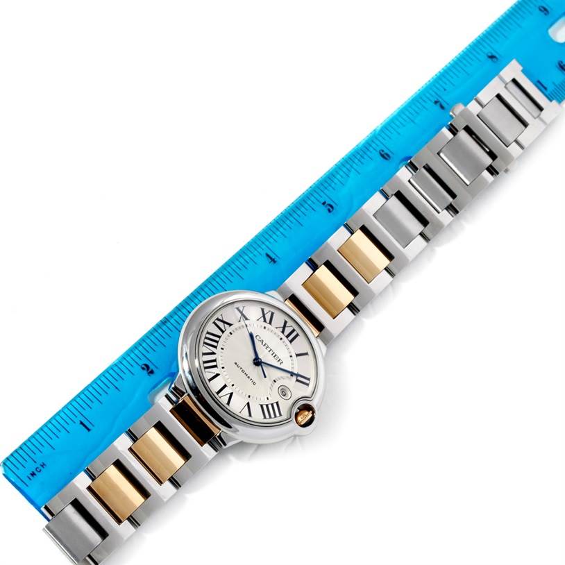 The image shows a Cartier Ballon Bleu W69009Z3 Men
s Stainless Steel Silver Dial W69009Z3 Men
s Stainless Steel Silver Dial watch laid flat next to a ruler, highlighting its two-tone bracelet and circular dial from a top view.